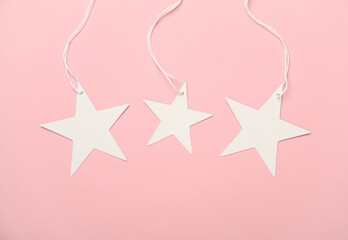 White tags on string in the shape of stars on pink background