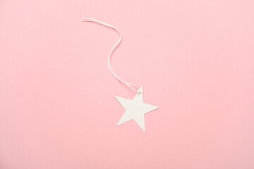 White tag on string in the shape of star on pink background