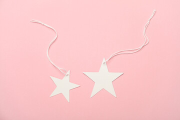White tags on string in the shape of stars on pink background