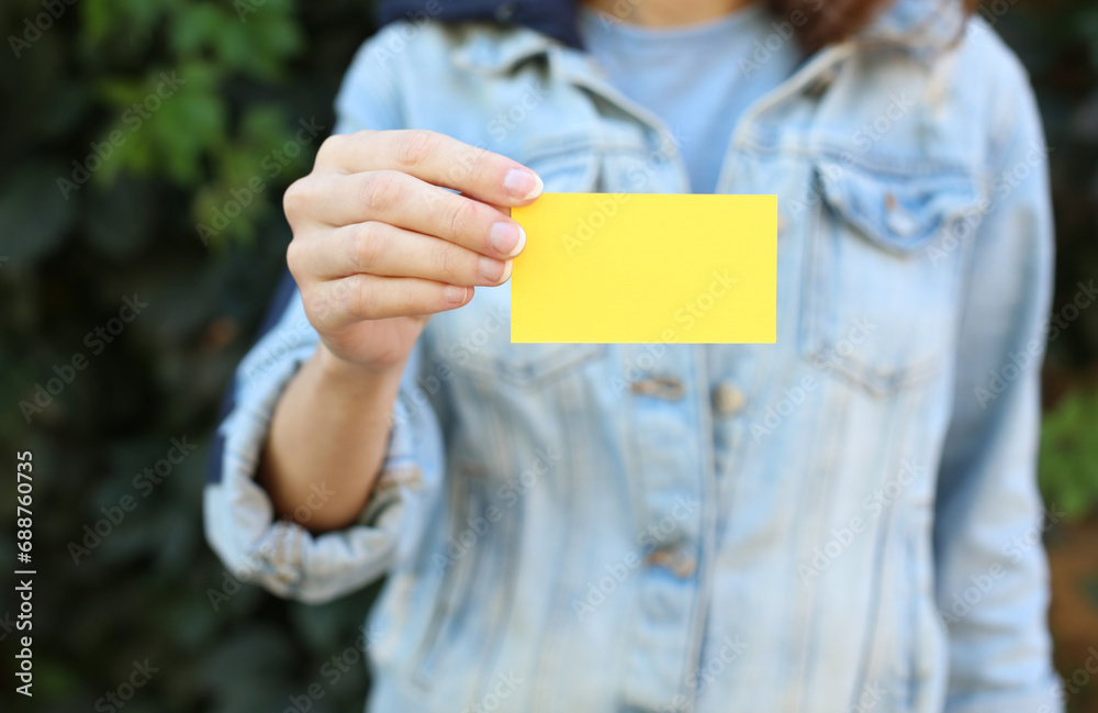 Wall mural woman in jeans jacket holding business card against green plants wall background