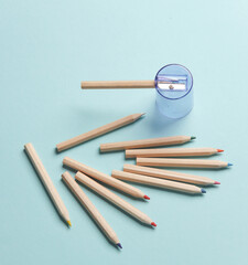 wooden colored pencils and sharpener on a blue background. Creativity, art