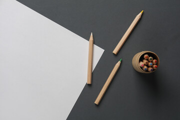 Box with wooden colored pencils and paper sheet on dark gray background. Creativity, art. Top view