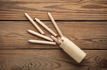 Box with wooden colored pencils on wooden background. Creativity, art. Top view