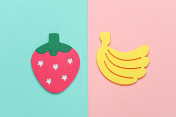 Handmade felt strawberries and bananas on a pink blue background