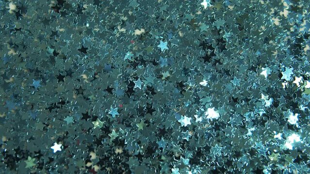 Silver and blue metal stars. Colorful particles such as confetti or sparkles. Silver holiday background. Shiny texture. Particle background. Shining sparkles. Concept for birthday.