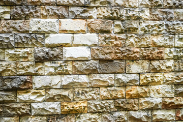 Texture of a stone wall with moss and fungal mold. Old castle stone wall. Pattern beech color of natural style design decorative uneven cracked real rough stone wall surface.