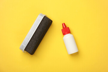 Shoe polish bottle and sponge on yellow background. Footwear care