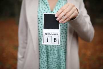Woman holds calendar with the date september 18 outdoors.
