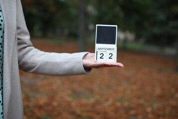 Woman holds calendar with the date september 22 outdoors.