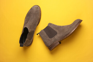 Gray suede Chelsea boots on yellow background. Top view