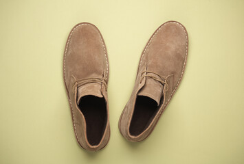 Suede desert shoes on a beige-green background. Top view