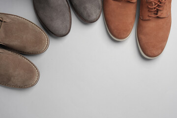 Three pairs of suede boots on a gray background. Copy space