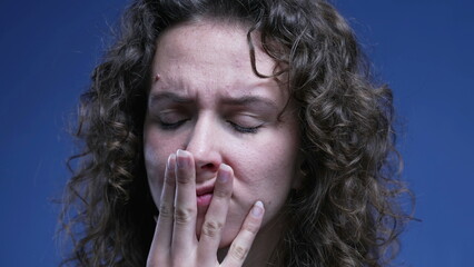 Anxious woman close-up face covering mouth with hand with preoccupied pensive expression, 20s...
