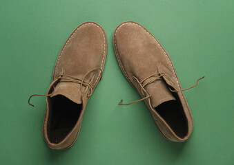 Suede desert boots on green background.