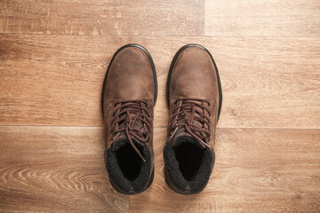 Men's leather winter boots on a wooden floor. Top view
