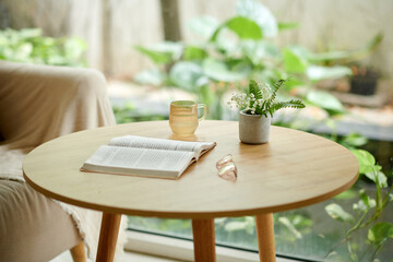 Glasses, book and cup of fresh water on small wooden table