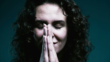 Faithful woman opening eyes to sky in PRAYER. Close-up face 20s person having HOPE during difficult...