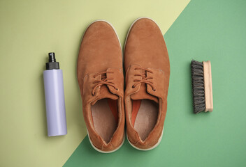 Suede shoes with brush and spray bottle on green background. Shoe care