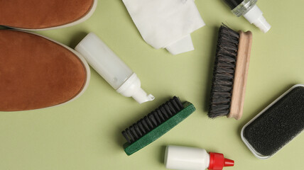 Suede shoes with Shoe care products and accessories on green background