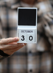 Woman in warm shirt holds calendar with date October 30
