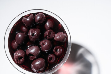Delicious dark cherries in kirsch served in a fine glass bowl, isolated on a white background.  Top view.