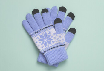 Purple winter gloves with patterns on blue color background