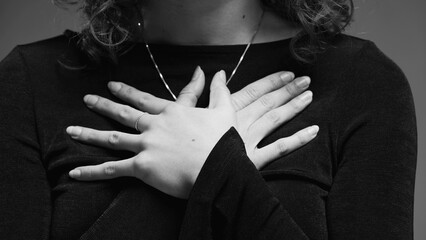 Heartwarming Gratitude Gesture by Woman, Hands on Chest in Close-up in artistic black and white
