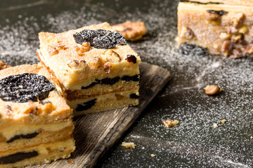 Cake with prunes and nuts. Pieces of delicious cake on a wooden plate. Decoration for the New Year and Christmas table.