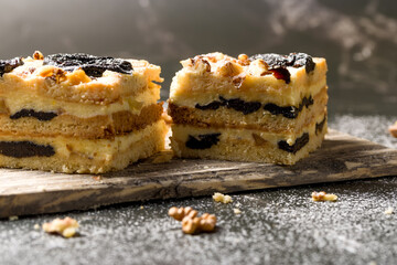Cake with prunes and nuts. Pieces of delicious cake on a wooden plate. Decoration for the New Year and Christmas table.