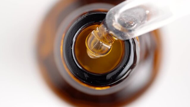 Close up of pipette and the serum bottle. Macro shot of serum gel in pipette falling in the bottle. Health care cosmetics.