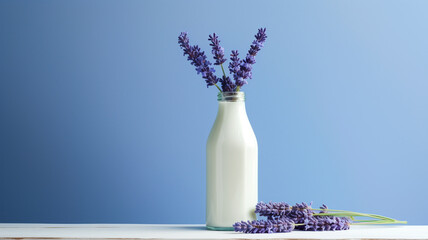 bottle and glass of fresh lavender flowers on light background