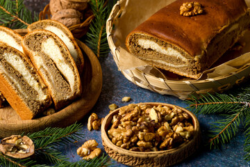 Obraz na płótnie Canvas Home baked walnut roll. Sliced traditional walnut roll on the background of Christmas tree branches