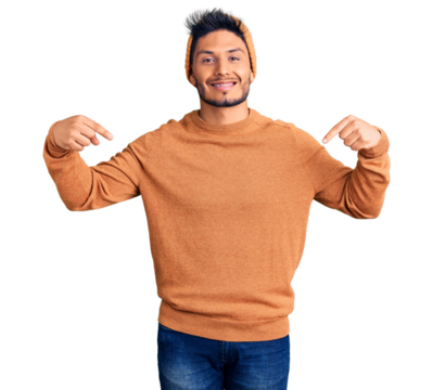 Handsome latin american young man wearing winter sweater and wool hat looking confident with smile on face, pointing oneself with fingers proud and happy.