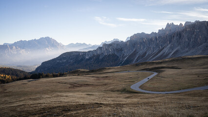 High mountain pass with curving road during early foggy morning, Dolomites, Italy