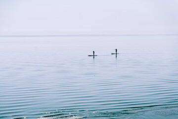 Fototapeta na wymiar Two people are surfing on the calm waters of the sea. Togliatti, Russia - 30 Sep 2023
