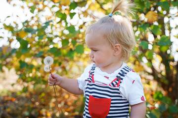 Cute child girl baby toddler In a striped jumpsuit walks outdoors in summer 