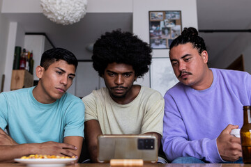 Anxious men watching game over mobile phone at home