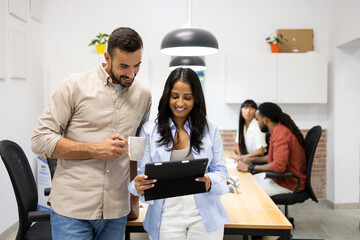 Multiracial colleagues discussing over tablet in meeting