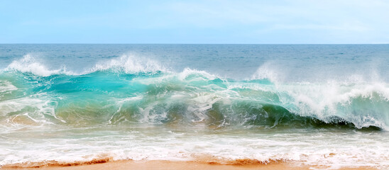 Blue and aquamarine color sea waves and yellow sand  with white foam. Marine beach background. Banner format.