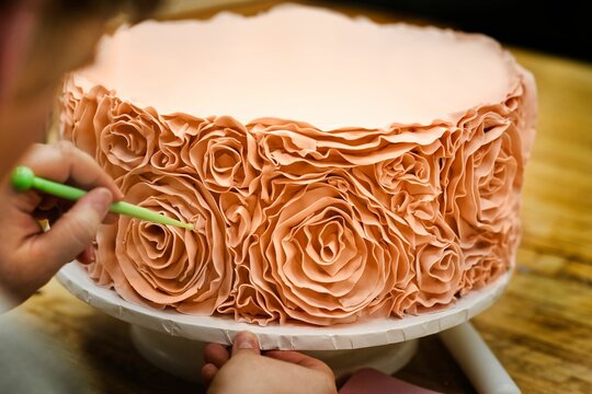 Close-up image of a beautiful cake being created, decorating a delicious cake with fondant roses
