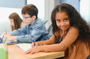 African American School Girl Writing Learning Sitting At Desk In Classroom Indoors