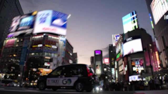 SHIBUYA, TOKYO, JAPAN - NOV 2023 : Shibuya Crossing in sunset. Crowd of people, car, taxi and bike at the street. Time lapse shot, dusk to night. Japanese urban city life and transportation concept.