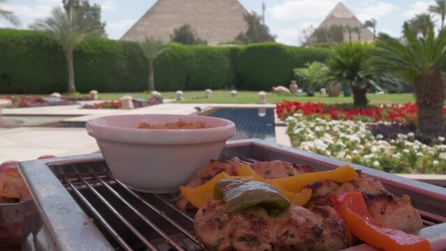 Egyptian food is on a table. Restaurant. Pyramids of Giza is on the background. Luxury hotel terrace with palms and view on a Great Pyramids. 