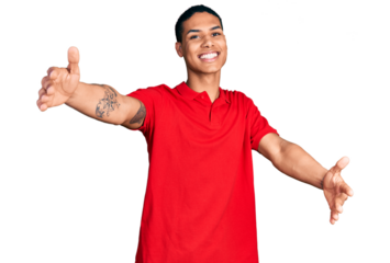 Young hispanic man wearing casual red t shirt looking at the camera smiling with open arms for hug. cheerful expression embracing happiness.