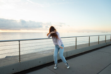Young woman dancing in front of the sea at sunrise.