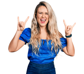 Young blonde woman wearing casual clothes shouting with crazy expression doing rock symbol with hands up. music star. heavy music concept.