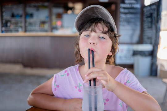 Child with straw in mouth sitting in cafe