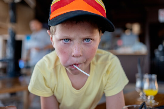 Serious child eating lollipop in cafe