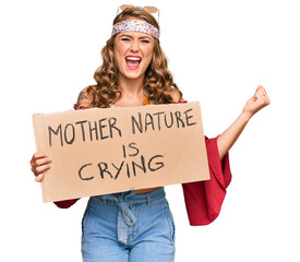 Young blonde girl wearing hippie style holding mother nature is crying protest cardboard banner...