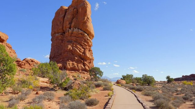 Establishing shot of mountain trail with red rocks background in Double Arch, Arches National Park, Utah, North America. Day time on October 2023. Still camera view. ProRes 422 HQ.